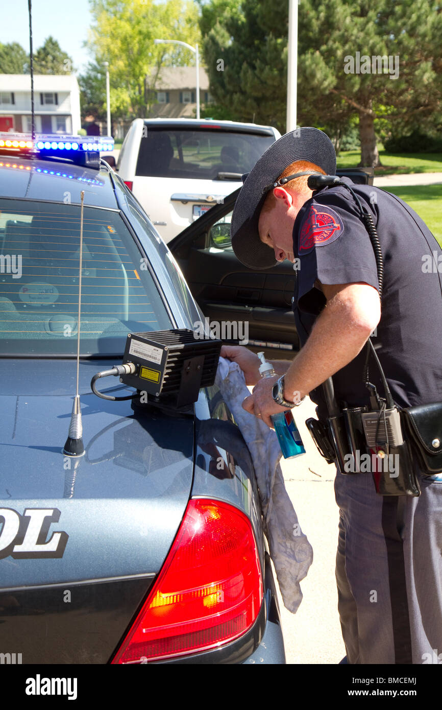 Nebraska State Trooper cleaning the Automated License Plate Reader that is mounted on his police cruiser. Stock Photo