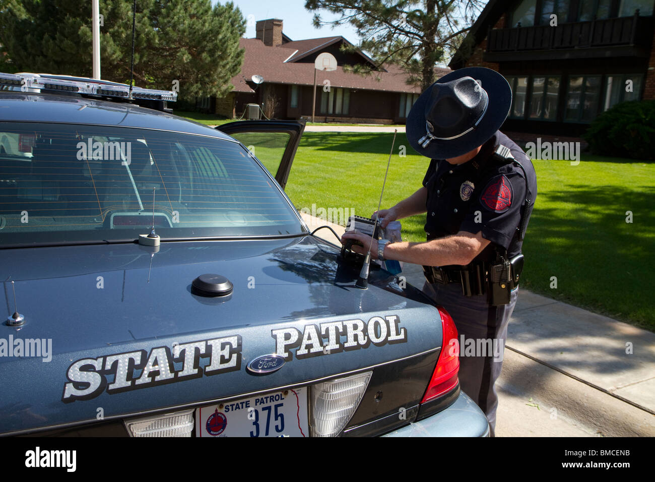 Nebraska State Trooper cleaning the Automated License Plate Reader that is mounted on his police cruiser. Stock Photo