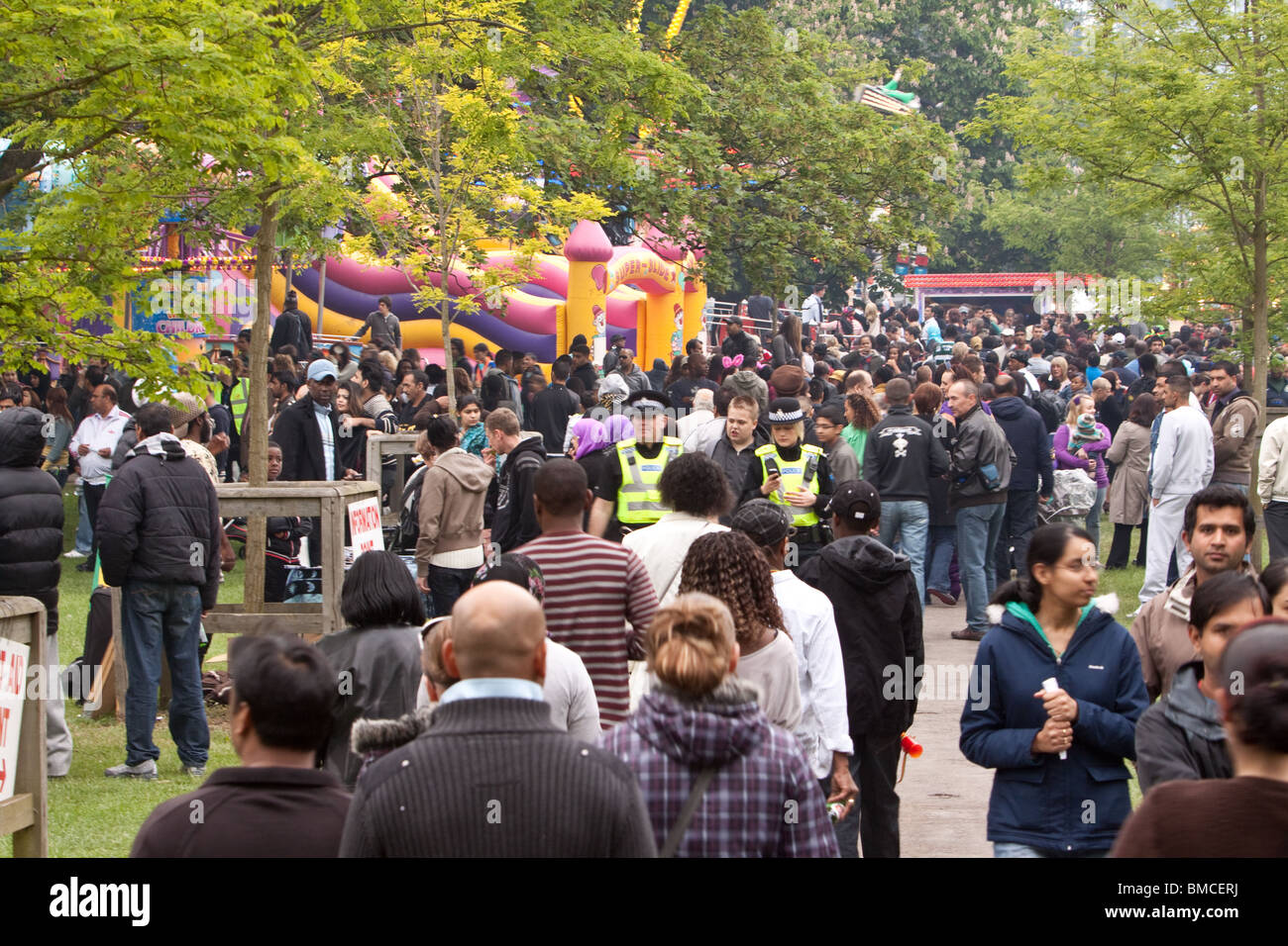 Two police officers lost in a large crowd of people Stock Photo