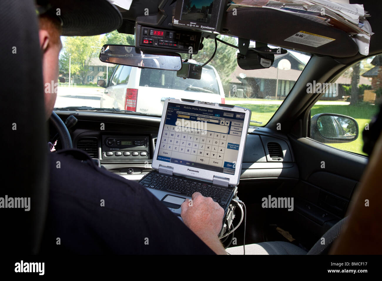 Nebraska State Trooper using laptop computer in cruiser to read output from an Automated License Plate Reader, LPR. Stock Photo