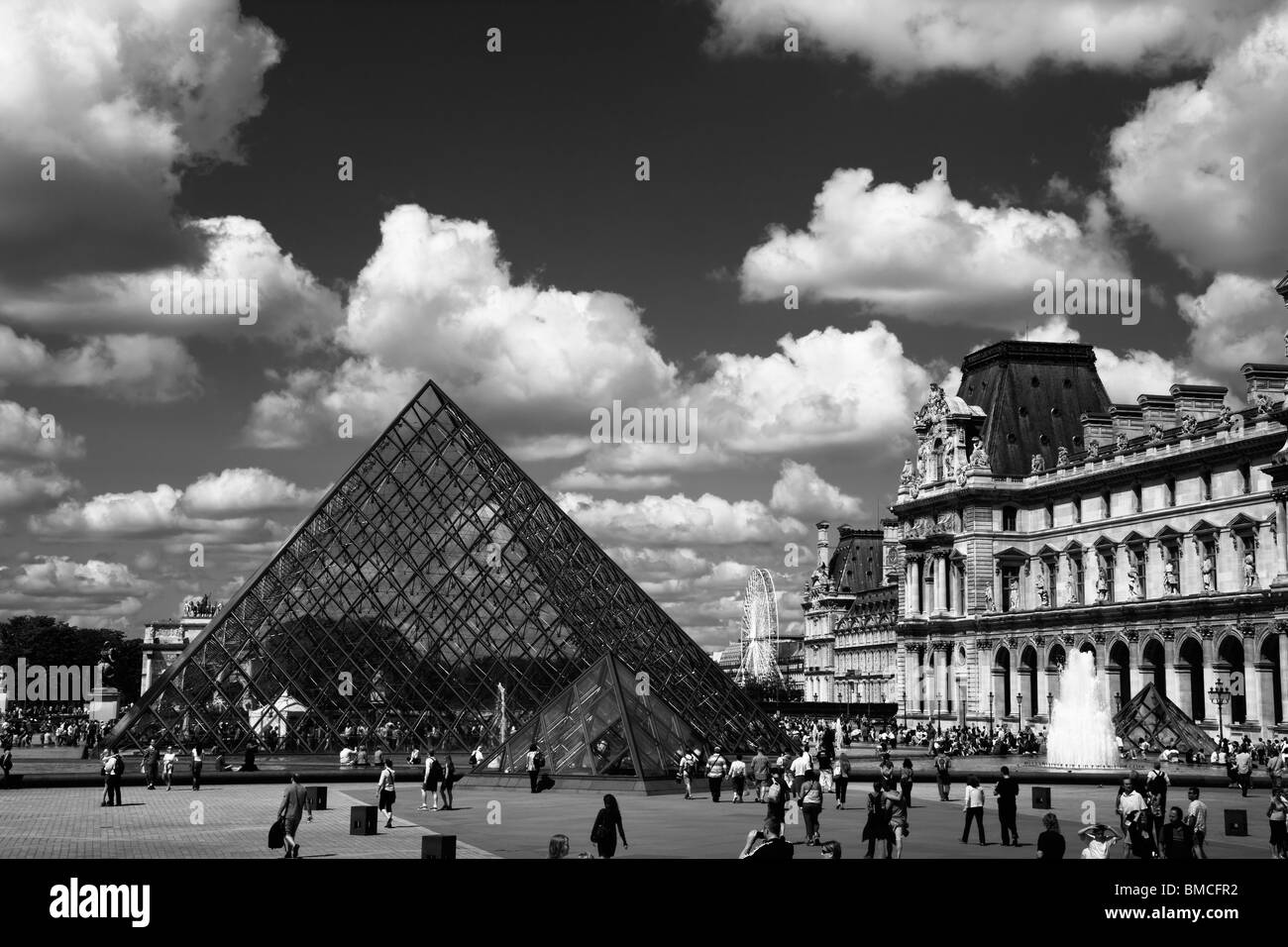 Dramatic Black and white Panoramic view of the Glass Pyramid and fountains of the Louvre beautiful dramatic sky  Paris France Stock Photo