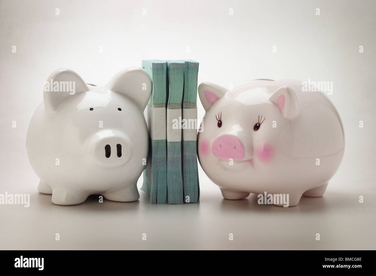 Two Piggy banks and stacks of paper money Stock Photo