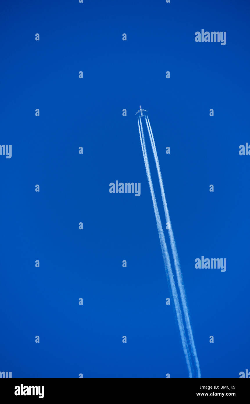 Airplane jet with contrail in a blue sky. Stock Photo