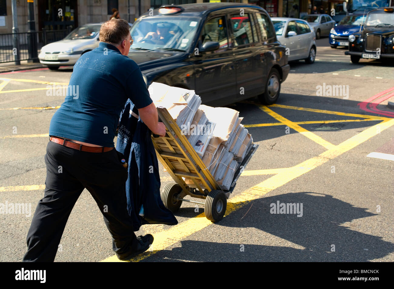 Newspaper delivery crossing busy main road, London, England, UK, Europe Stock Photo
