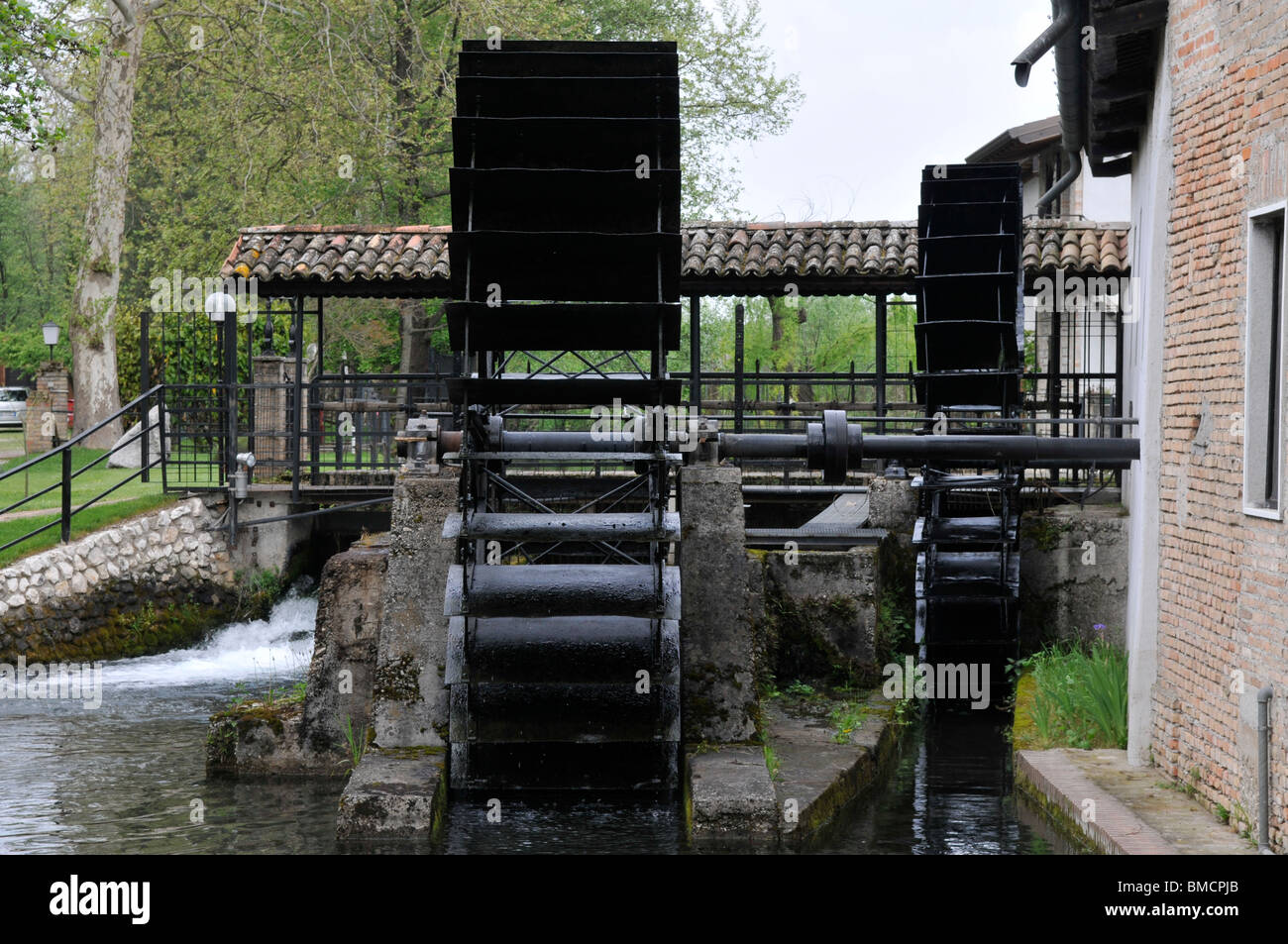 Two old millwheels in action powerd by renewable hydropower Stock Photo ...