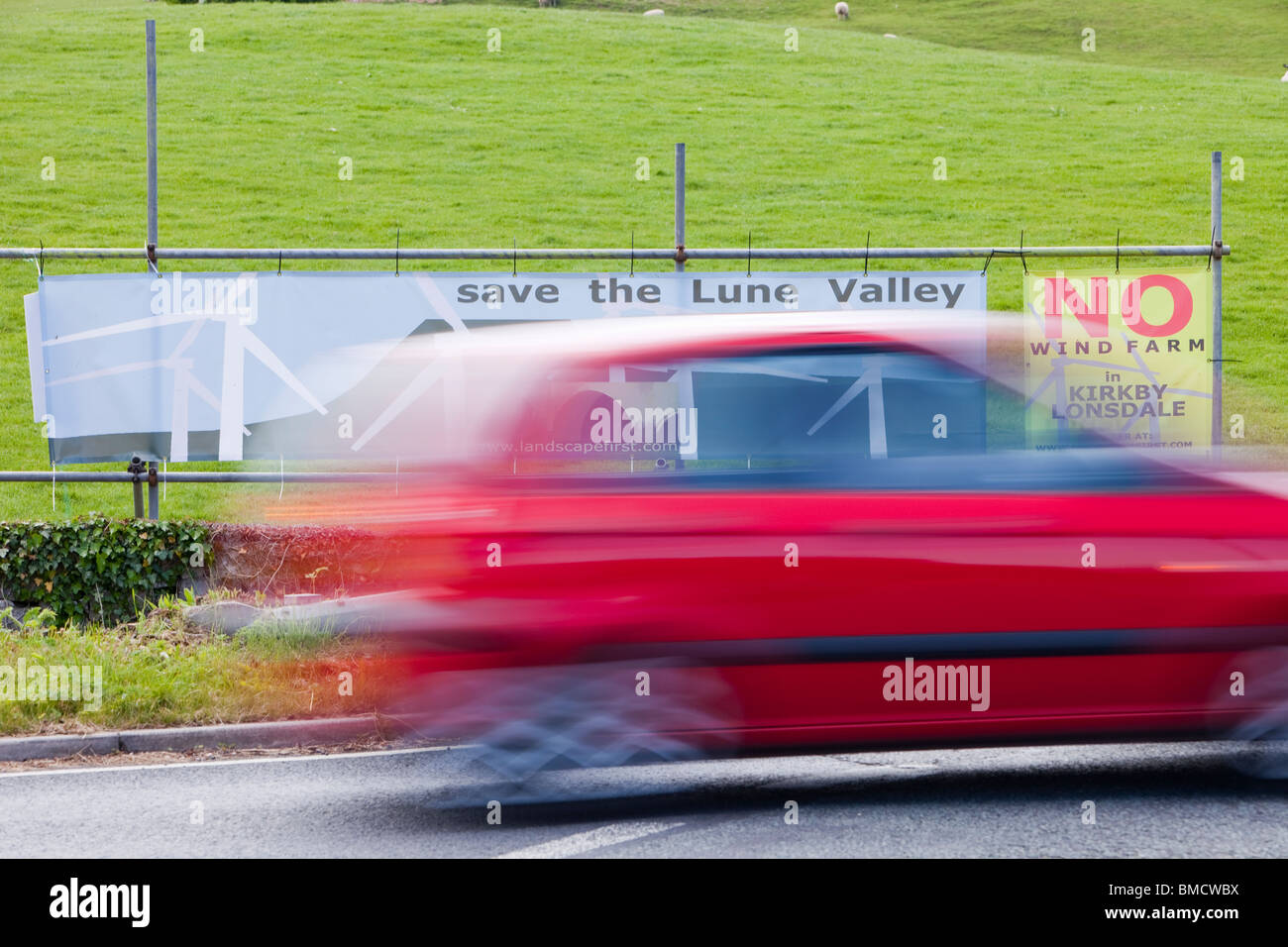 a Car passing banners protesting against a potential wind farm development near Kirkby Lonsdale, Cumbria, UK. Stock Photo