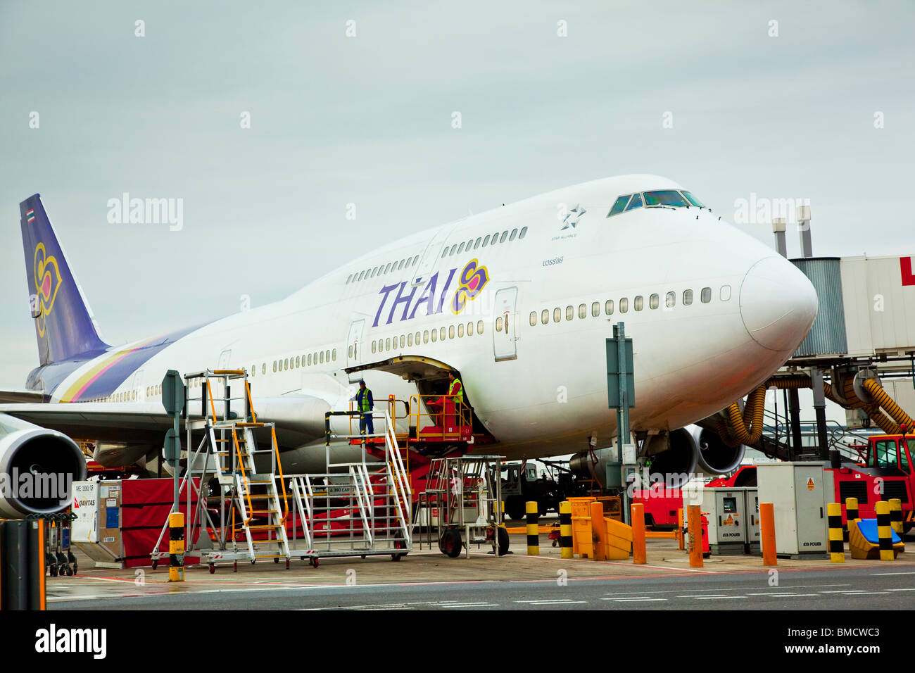 A Thai Airways Boeing 747-400 in the process of being loaded stands at a gate at Heathrow Airport London England Stock Photo