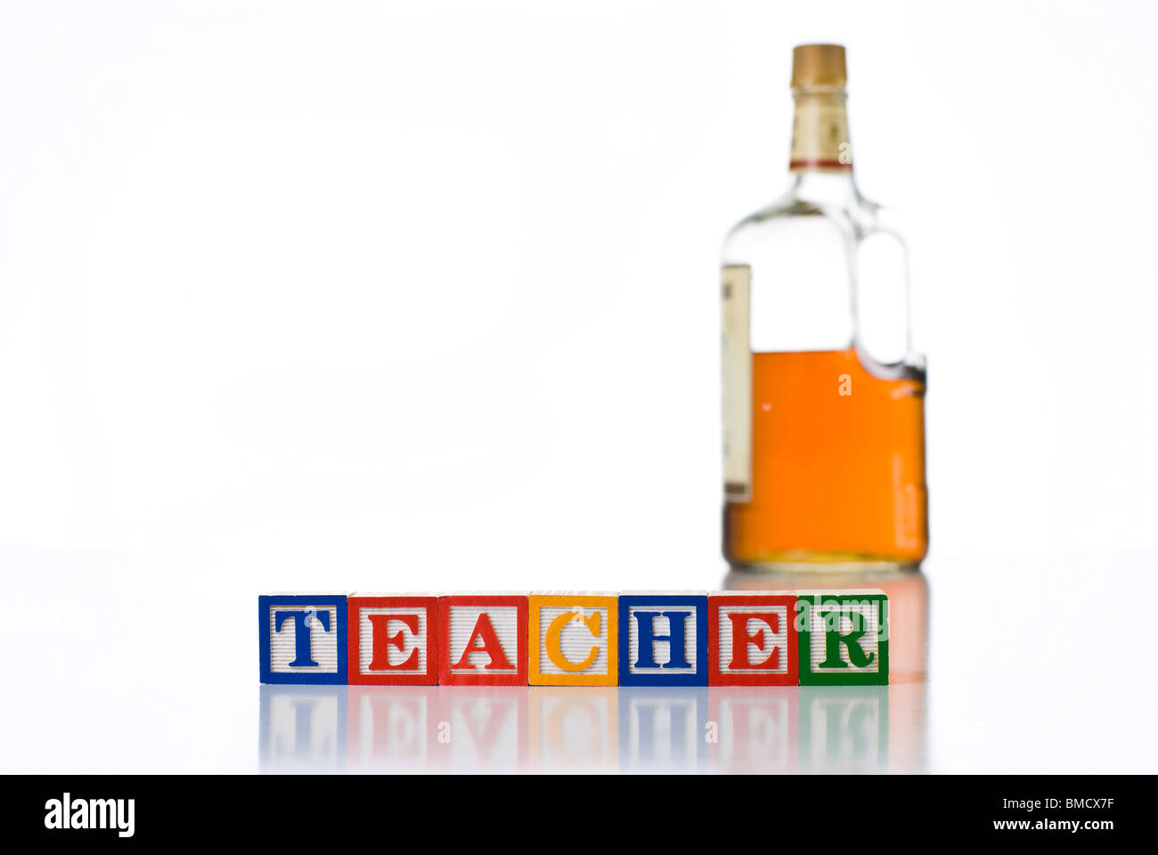 Colorful children's blocks spelling TEACHER with a bottle of liquor Stock Photo