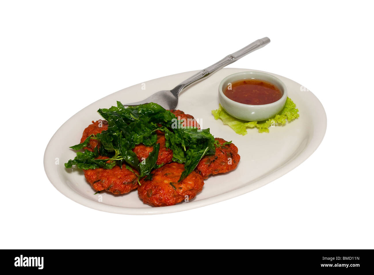 Tod Mun Pla (Thai fried fish patties) with sauce and fork cut out on a white background and surface Stock Photo