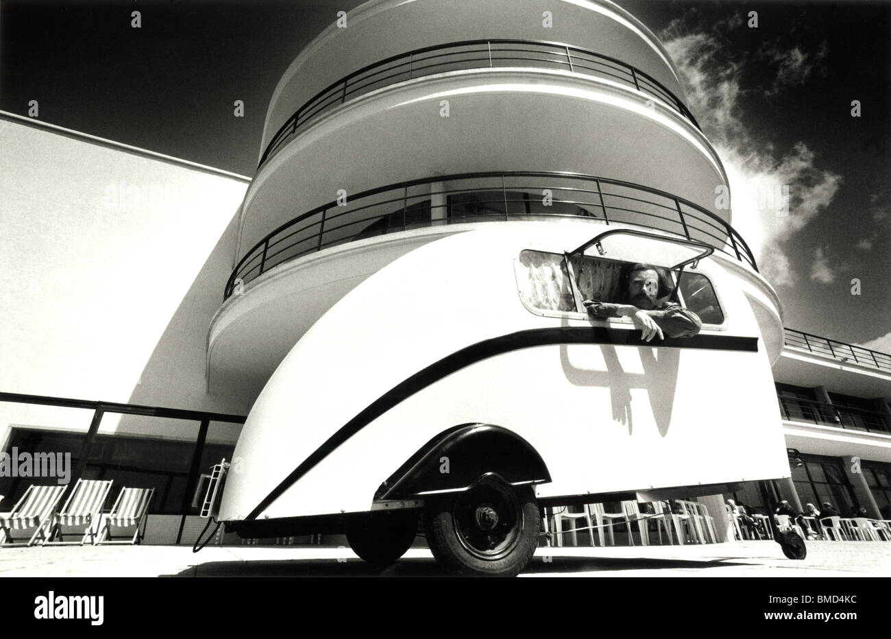 Man in a small deco-style caravan in front of very Art Deco De La Warr Pavilion, Bexhill On Sea, East Sussex, England. Stock Photo