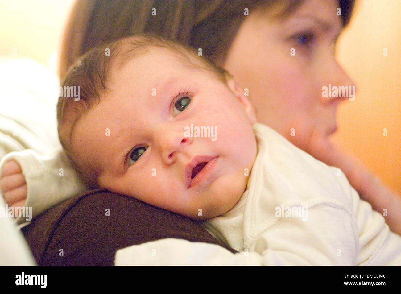 Baby daughter resting head on her mother’s shoulder Stock Photo