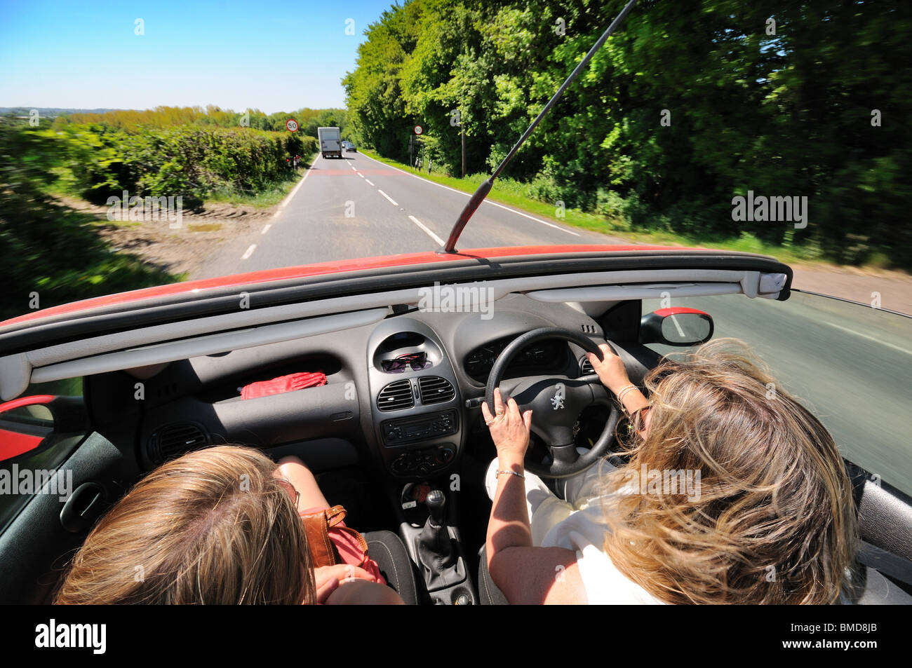 Open top car with female driver and passenger on open road Stock Photo