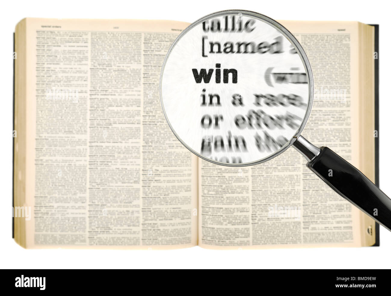 A magnifying glass on the word WIN on a dictionary. Isolated on white. Stock Photo