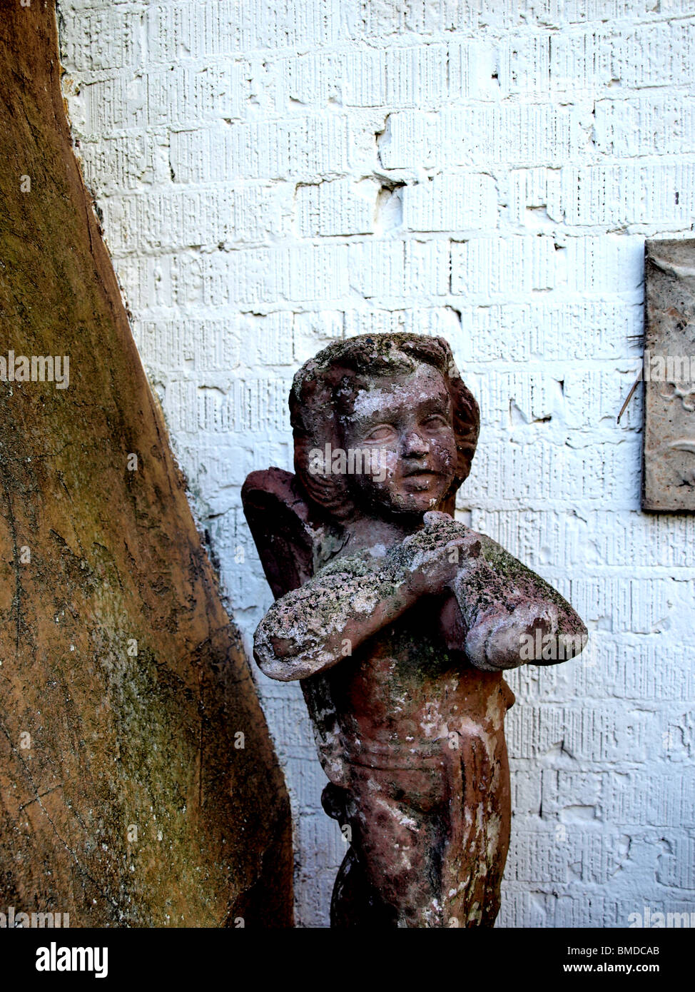 yard garden statue against white wall with male playing flute Stock Photo