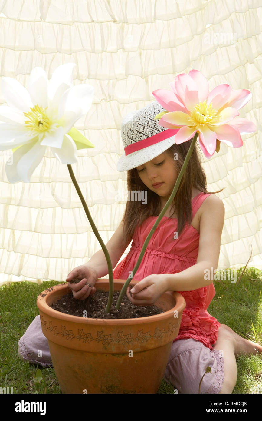 Girl playing with fake flowers in a flower pot Stock Photo