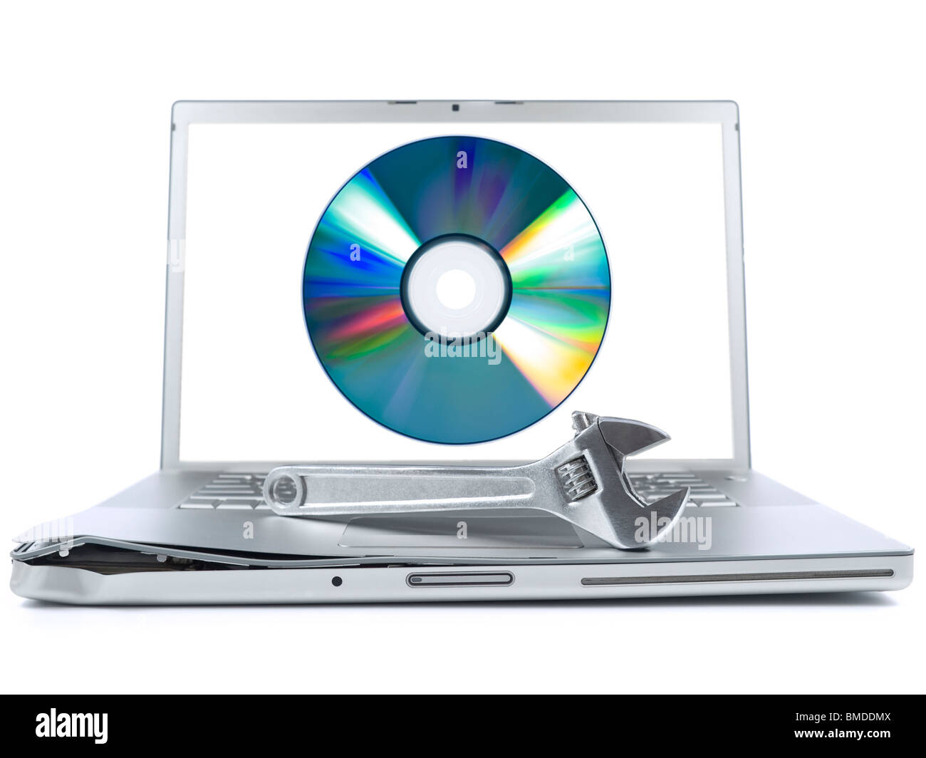 Damaged laptop with a spanner over it and a digital disc on the screen. Isolated on white. Stock Photo
