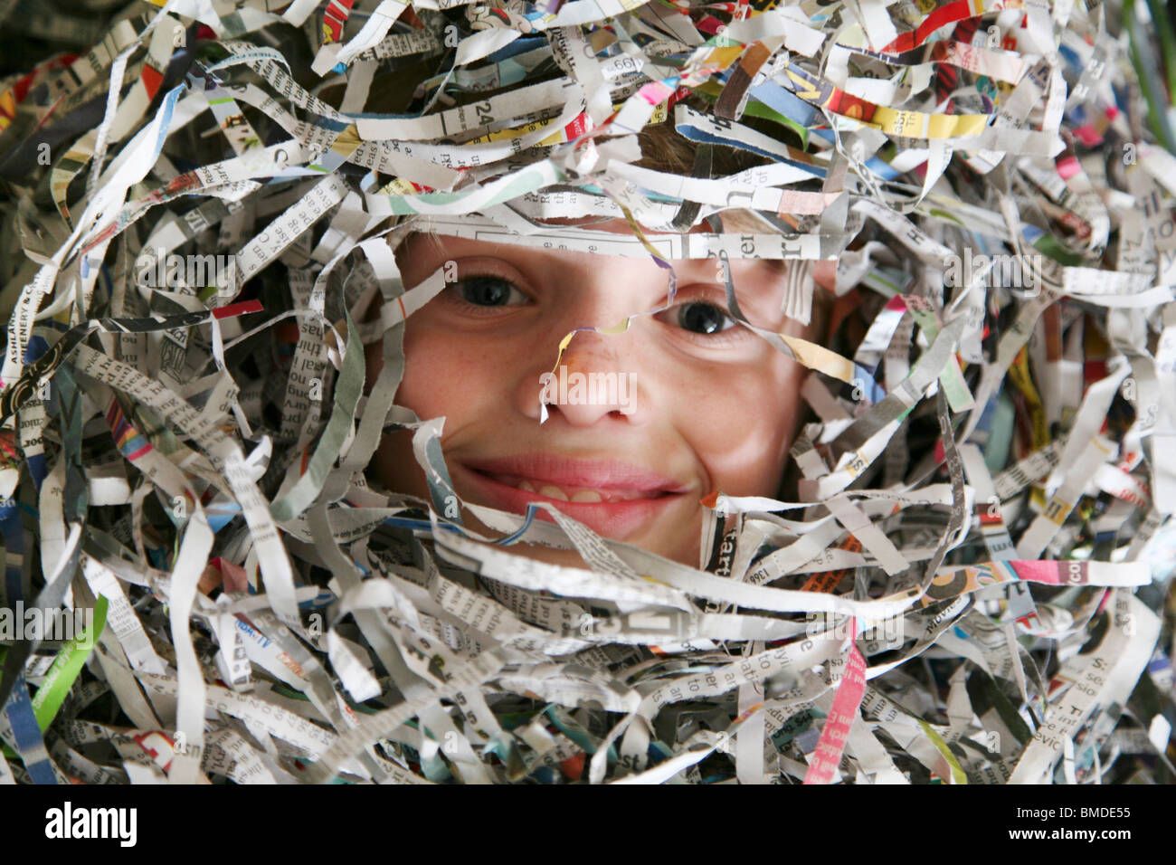 Girl looking through shredded newspapers Stock Photo