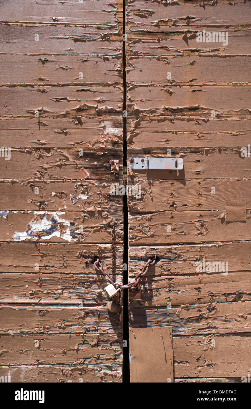 Detail of a padlocked, old weathered door with peeling paint in Encino, New Mexico. Stock Photo