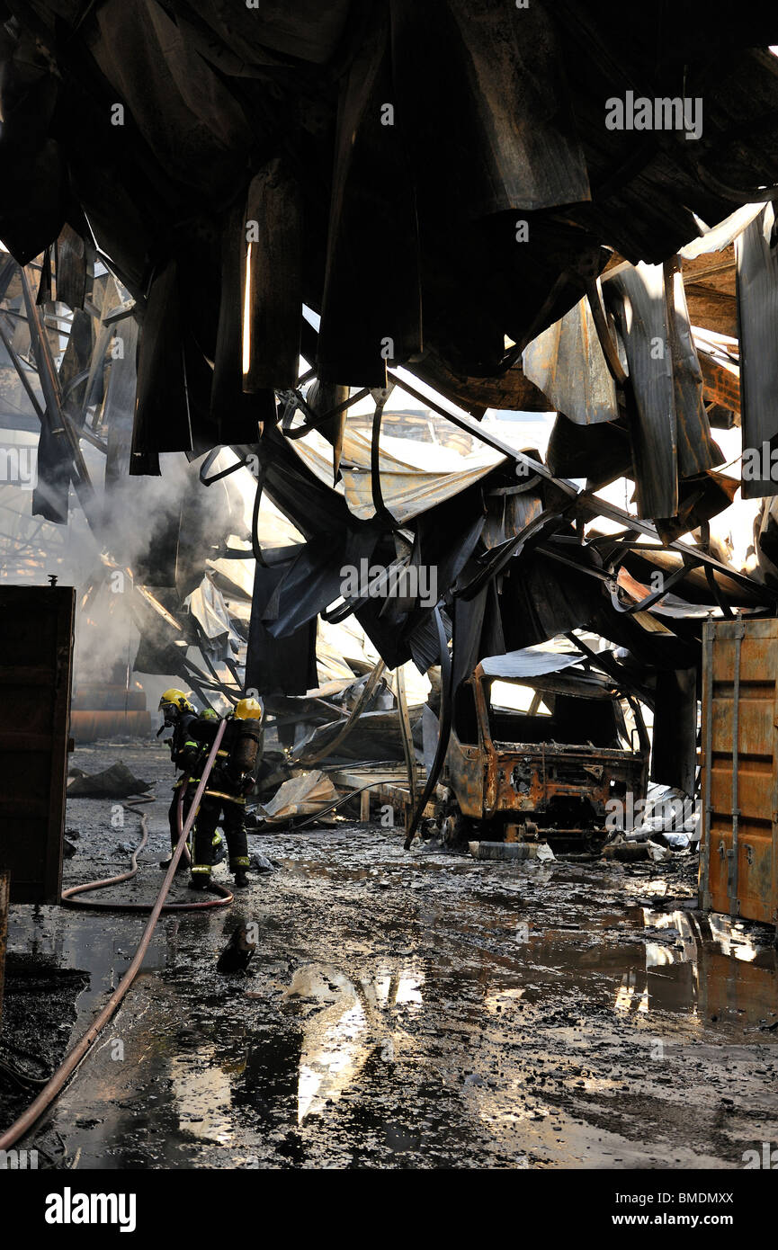 Firemen inside collapsed warehouse roof Stock Photo