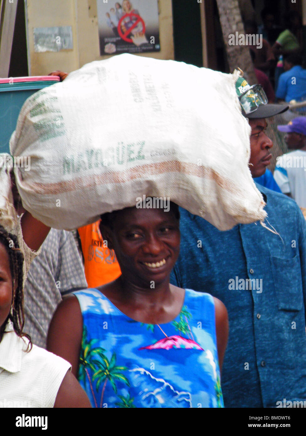 A smiling woman carries a sack across the Dominican Republic - Haiti border at Dajabon to sell in the weekly market Stock Photo
