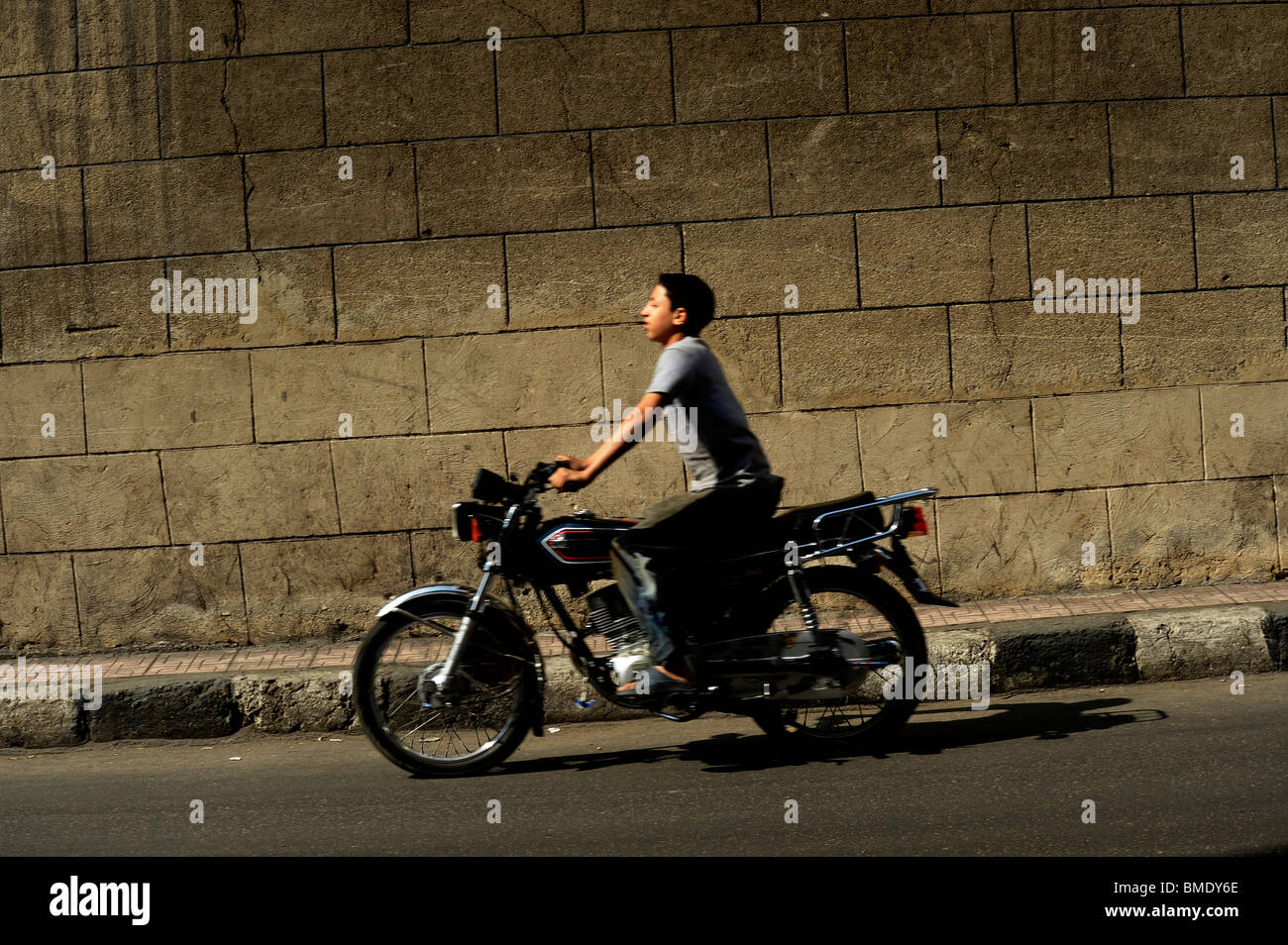 young boy riding his motorbike  ,back streets of the old district,Al Gamaliya, Islamic Cairo,egypt Stock Photo