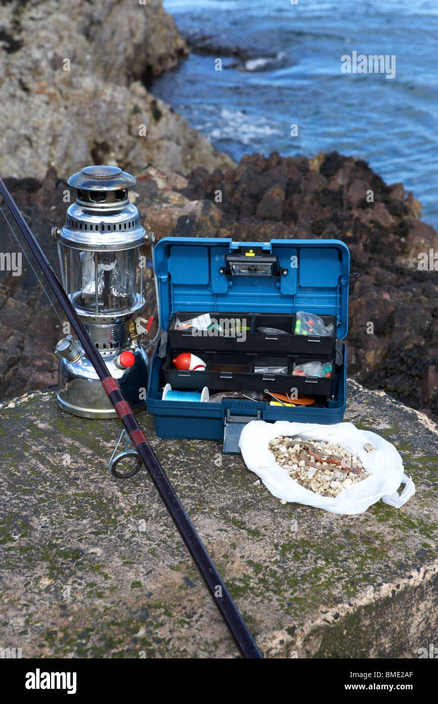fishing tackle box filled with sea fishing gear rod pressure lamp and bag of ragworm bait on the county antrim coast Stock Photo