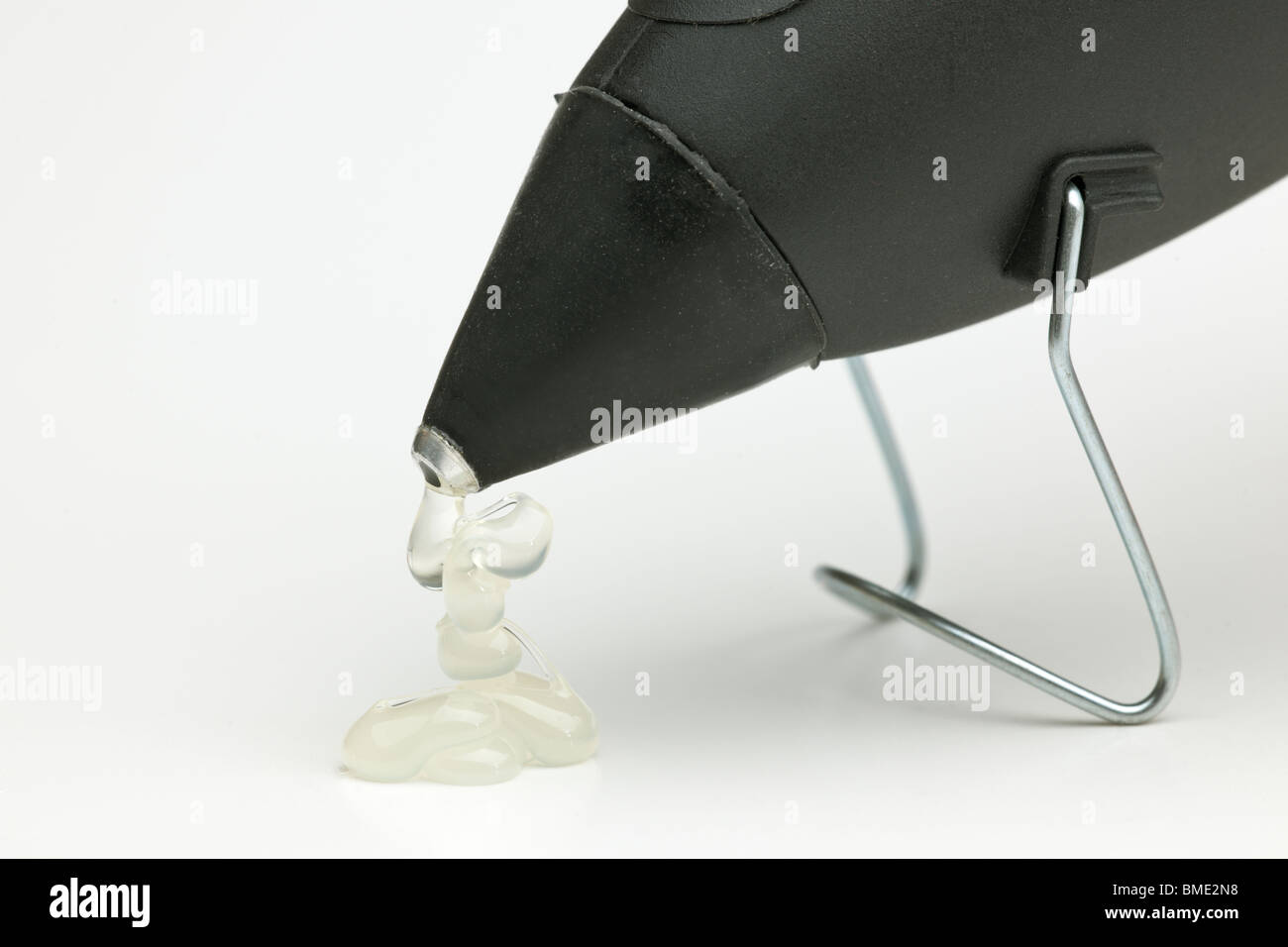 Hot glue pouring from the nozzle of a hot wax glue gun Stock Photo