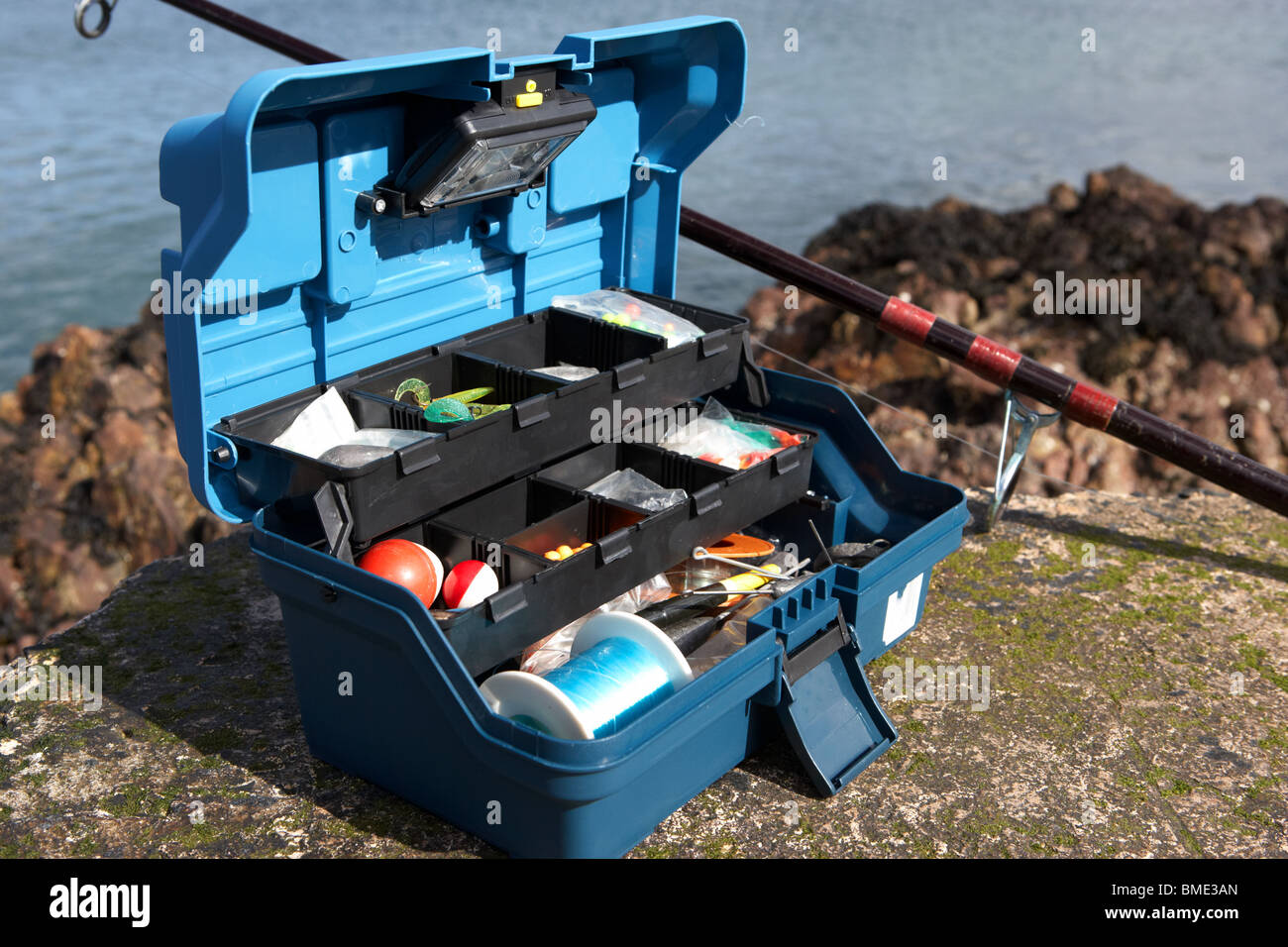 fishing tackle box filled with sea fishing gear and rod on the county  antrim coast northern ireland uk Stock Photo - Alamy