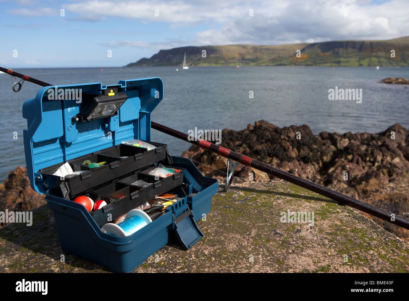 fishing tackle box filled with sea fishing gear and rod on the county antrim coast northern ireland uk Stock Photo