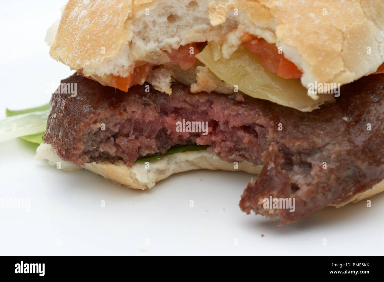 bite taken out of partially cooked home made hamburger showing raw meat Stock Photo