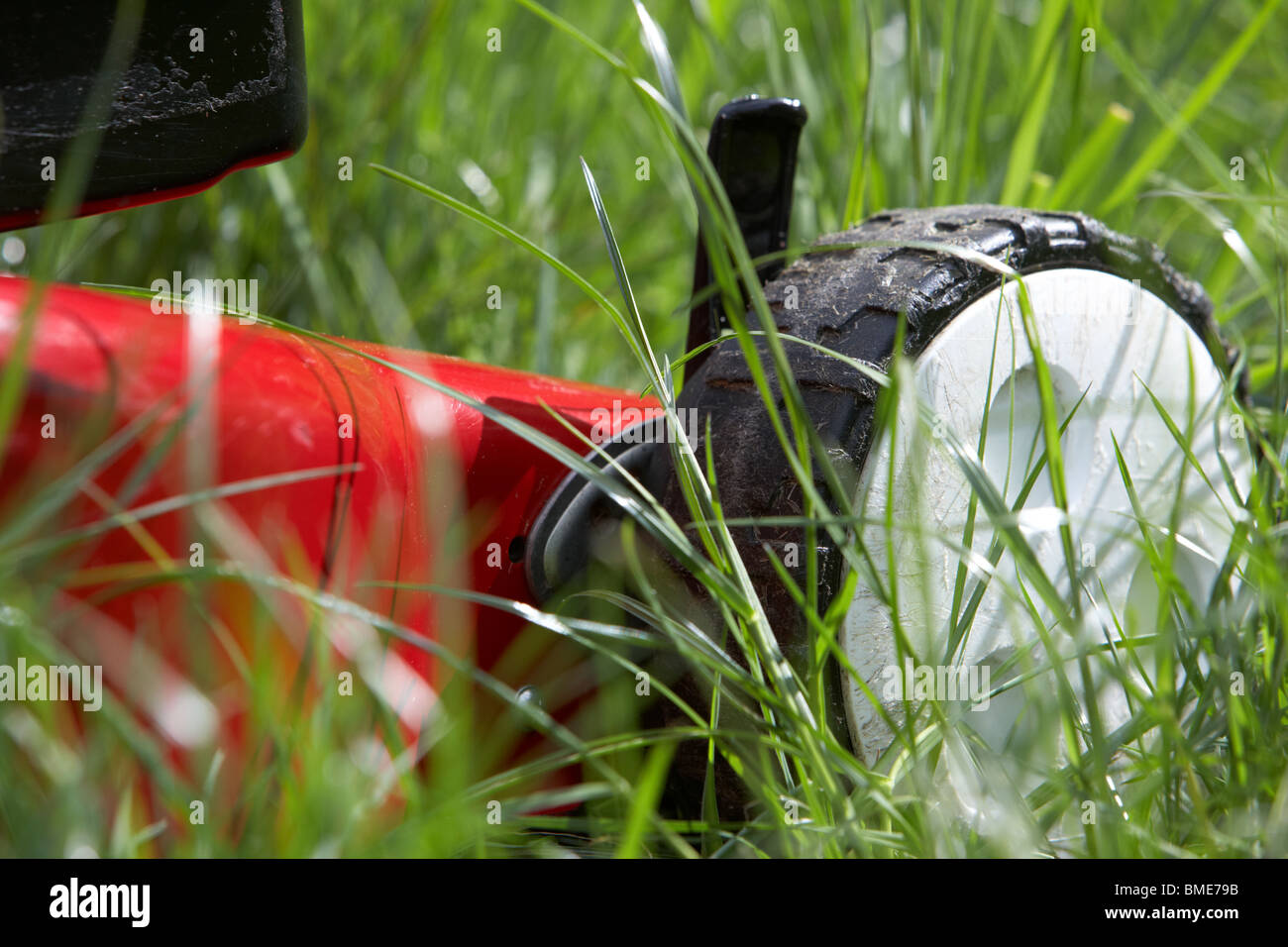 petrol lawnmower mowing deep long overgrown grass in a garden in the uk Stock Photo