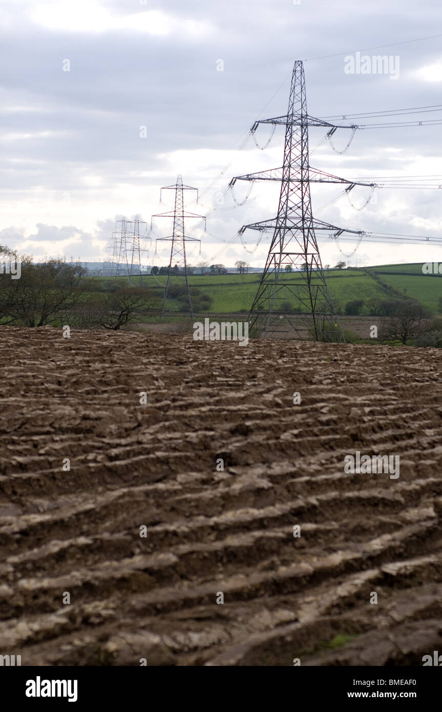 Electricity pylons in front of a ploughed field Stock Photo
