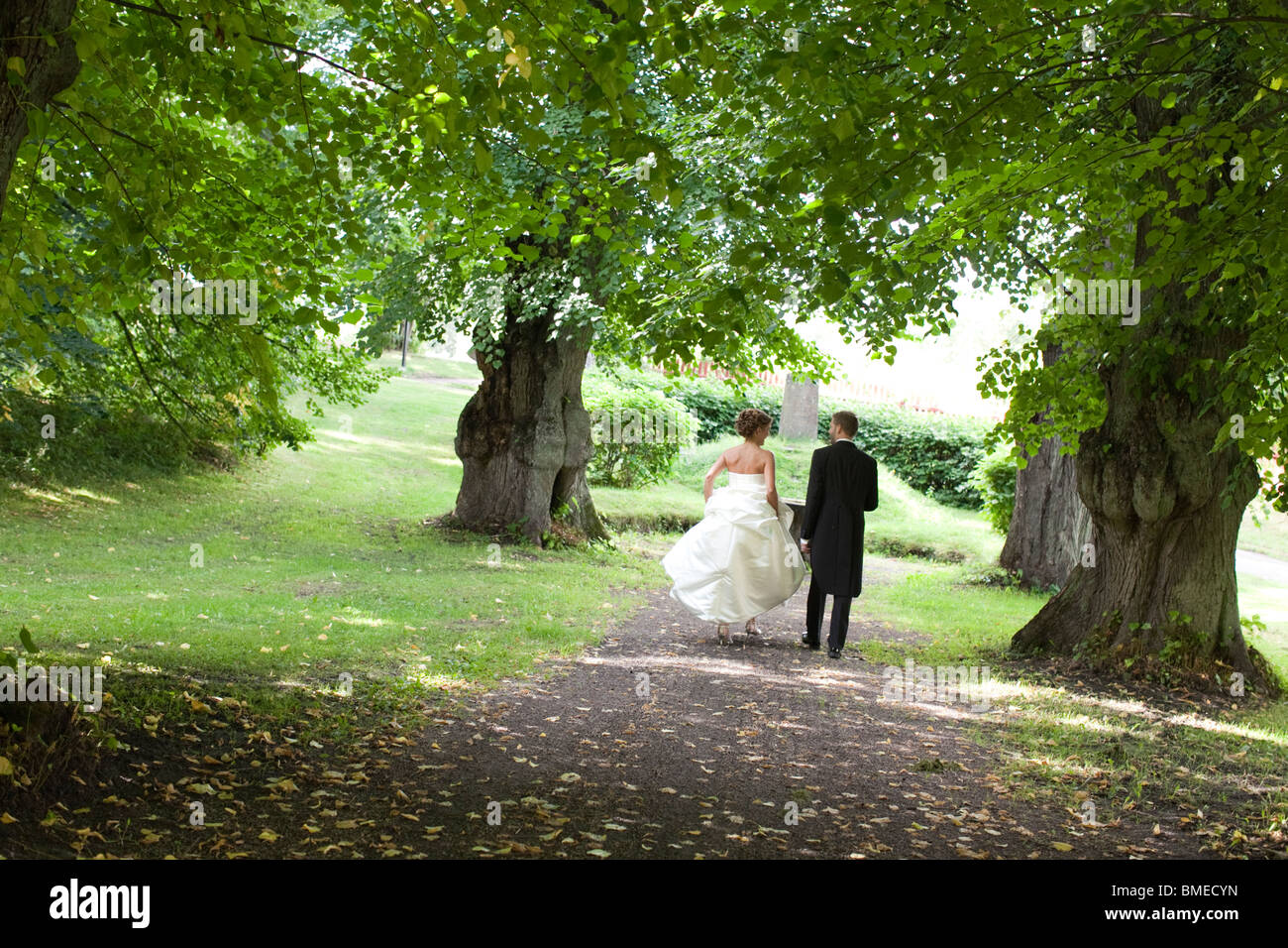 Bride and groom walking in park Stock Photo