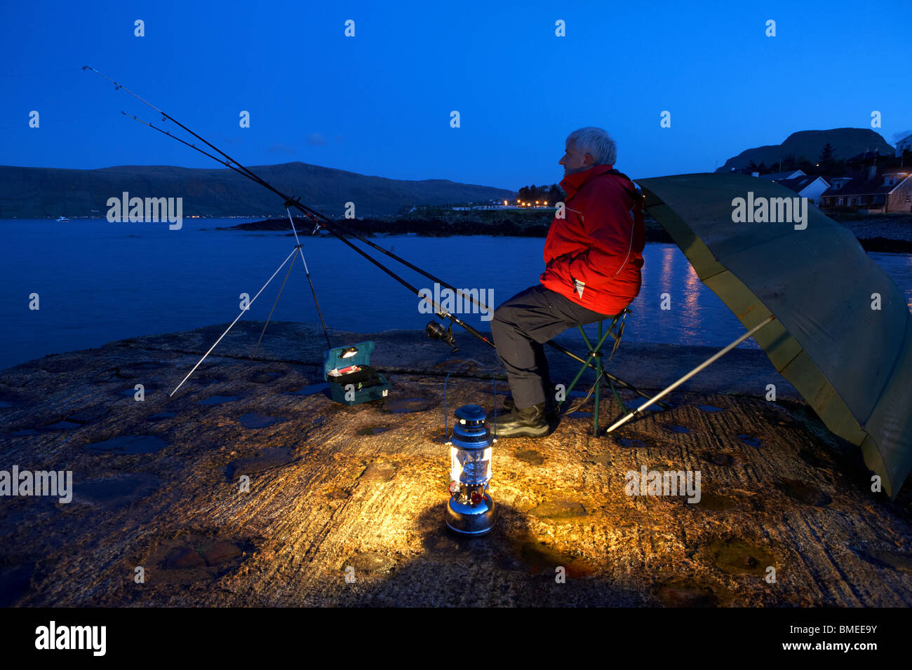 man nighttime fishing on the county antrim coast northern ireland uk at night Stock Photo