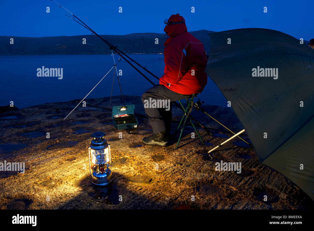 man nighttime fishing on the county antrim coast northern ireland uk Stock Photo