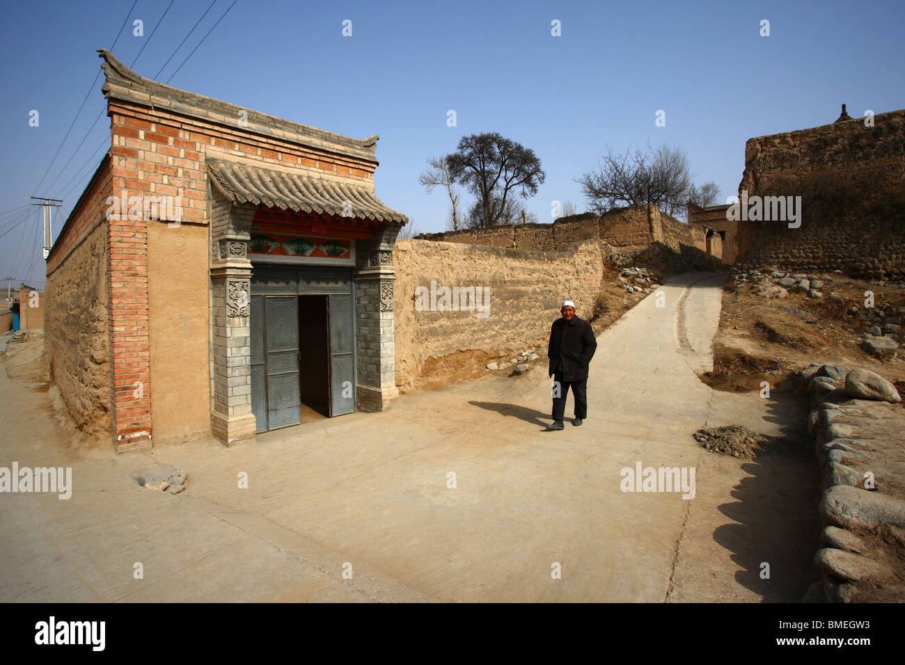 Elderly Bonan man walking in an alley, Dongxiang and Salar Autonomous County, Linxia, Gansu Province, China Stock Photo
