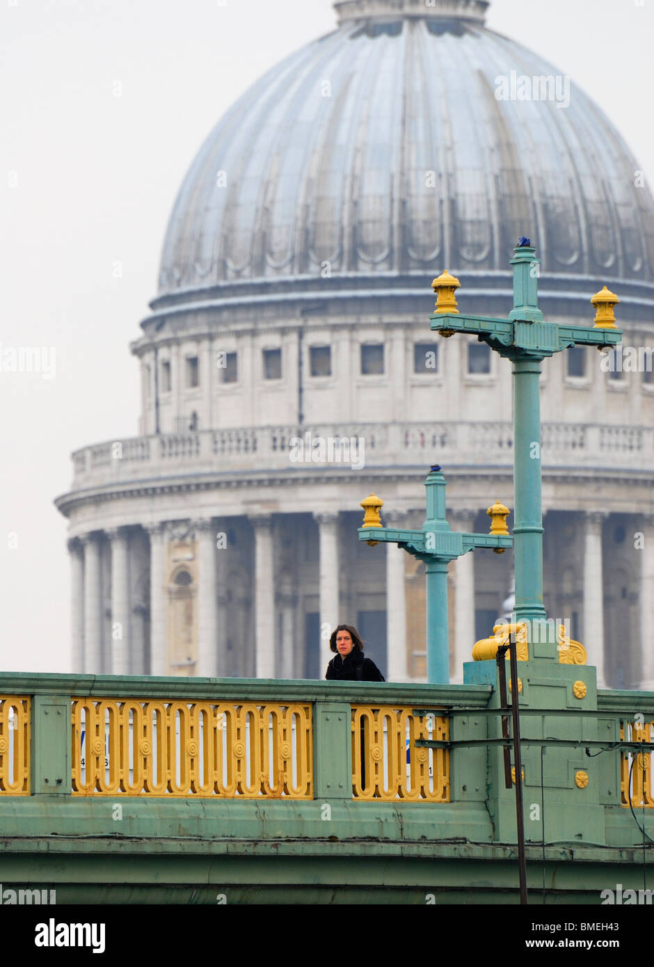 London, England, UK. Woman crossing Southwark Bridge; St Paul's Cathedral behind Stock Photo