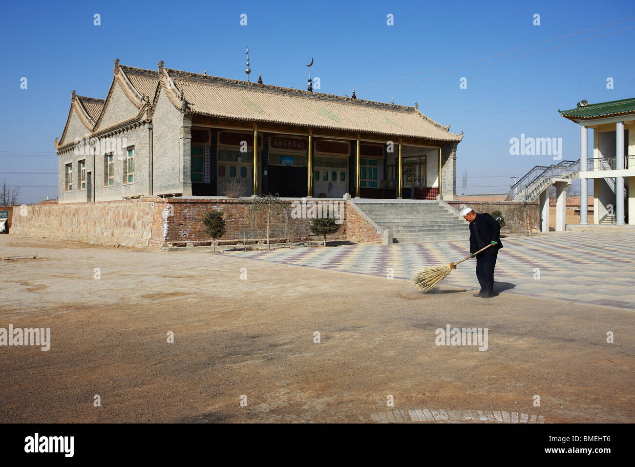 Hui man sweeping the courtyard of Mageda Mosque, Mageda Village, Tongxin, Wuzhong, Ningxia Province, China Stock Photo