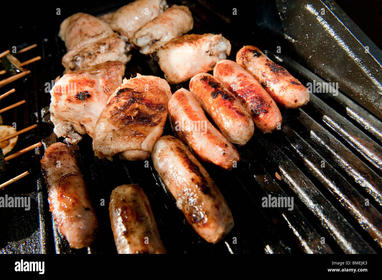 Sausages and chicken being cooked together on a barbecue Stock Photo