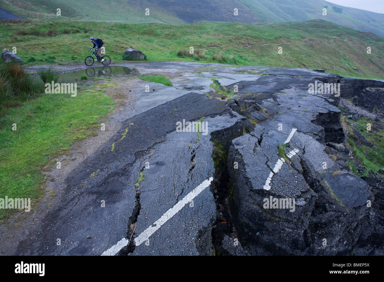 Cyclists struggle uphill near landslide road beneath Mam Tor in the