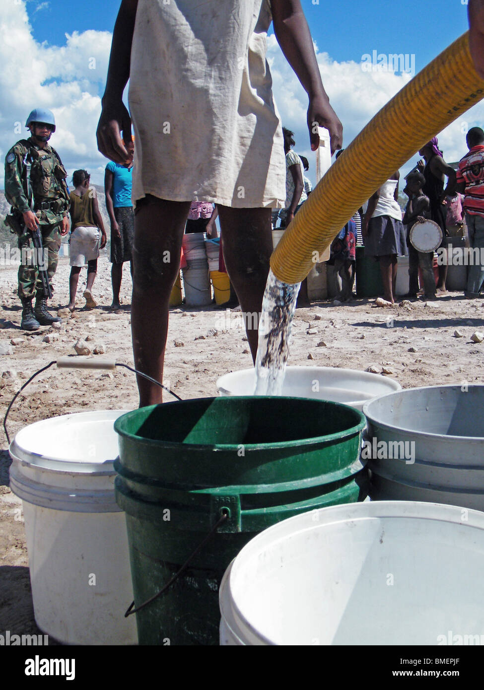 A girl watches as United Nations peacekeepers fill buckets with drinking water in the semi-desert outside Gonaives, Haiti Stock Photo
