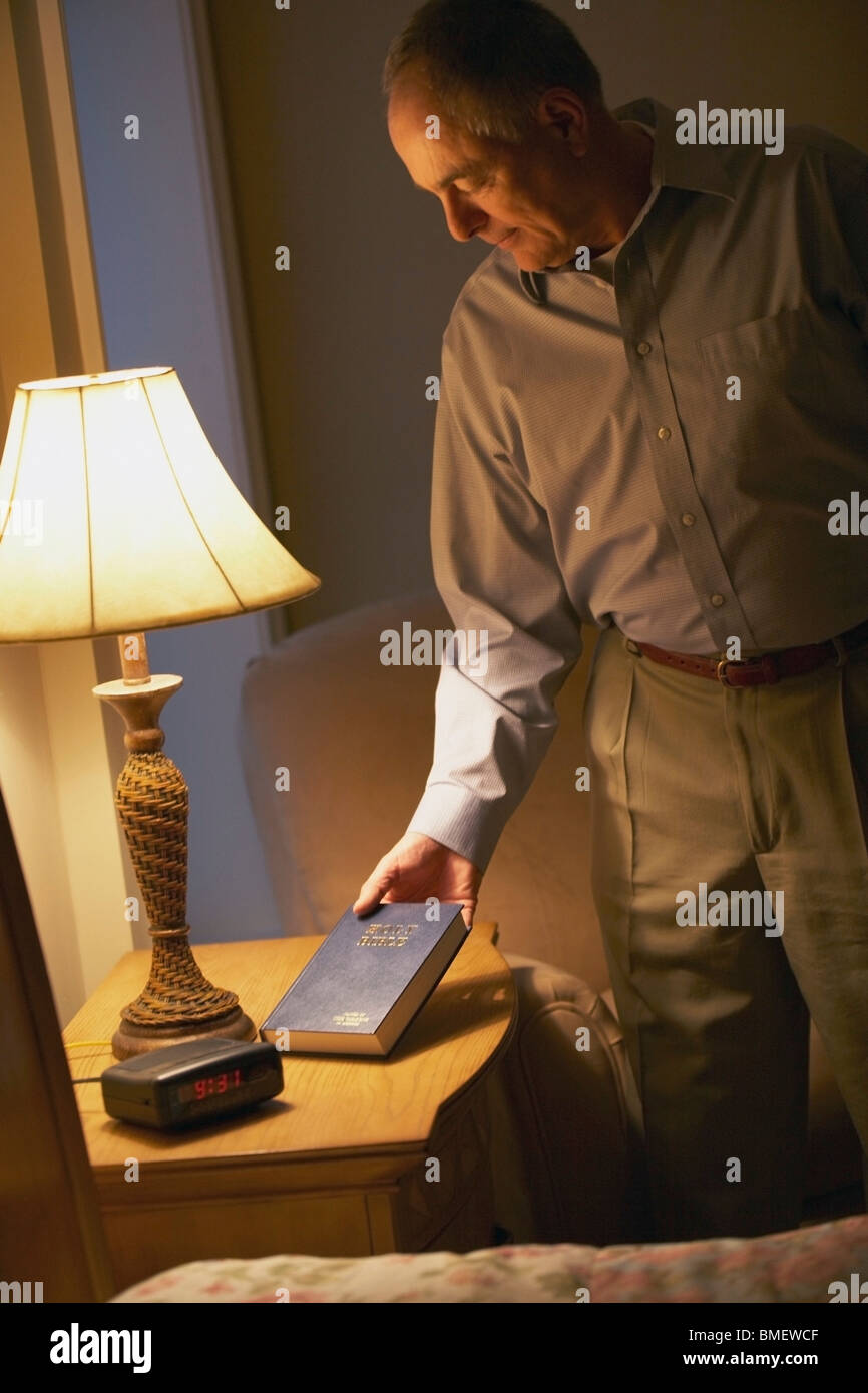 A Man Putting A Bible On The Night Stand Stock Photo