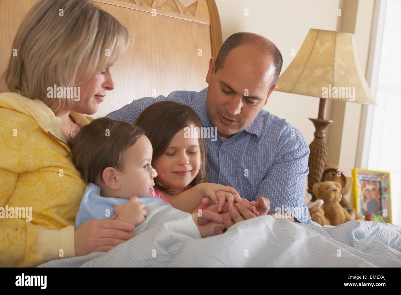 A Father And Mother Praying With Their Children At Bedtime Stock Photo ...