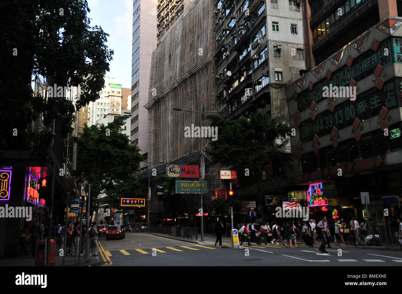 Late afternoon neon near a pedestrian crossing with people