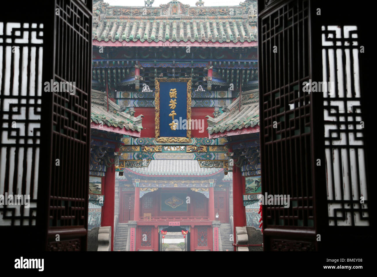View through lattice door towards memorial archway built in name of Guan Yu, Shanshangan Huiguan, Kaifeng, Henan, China Stock Photo