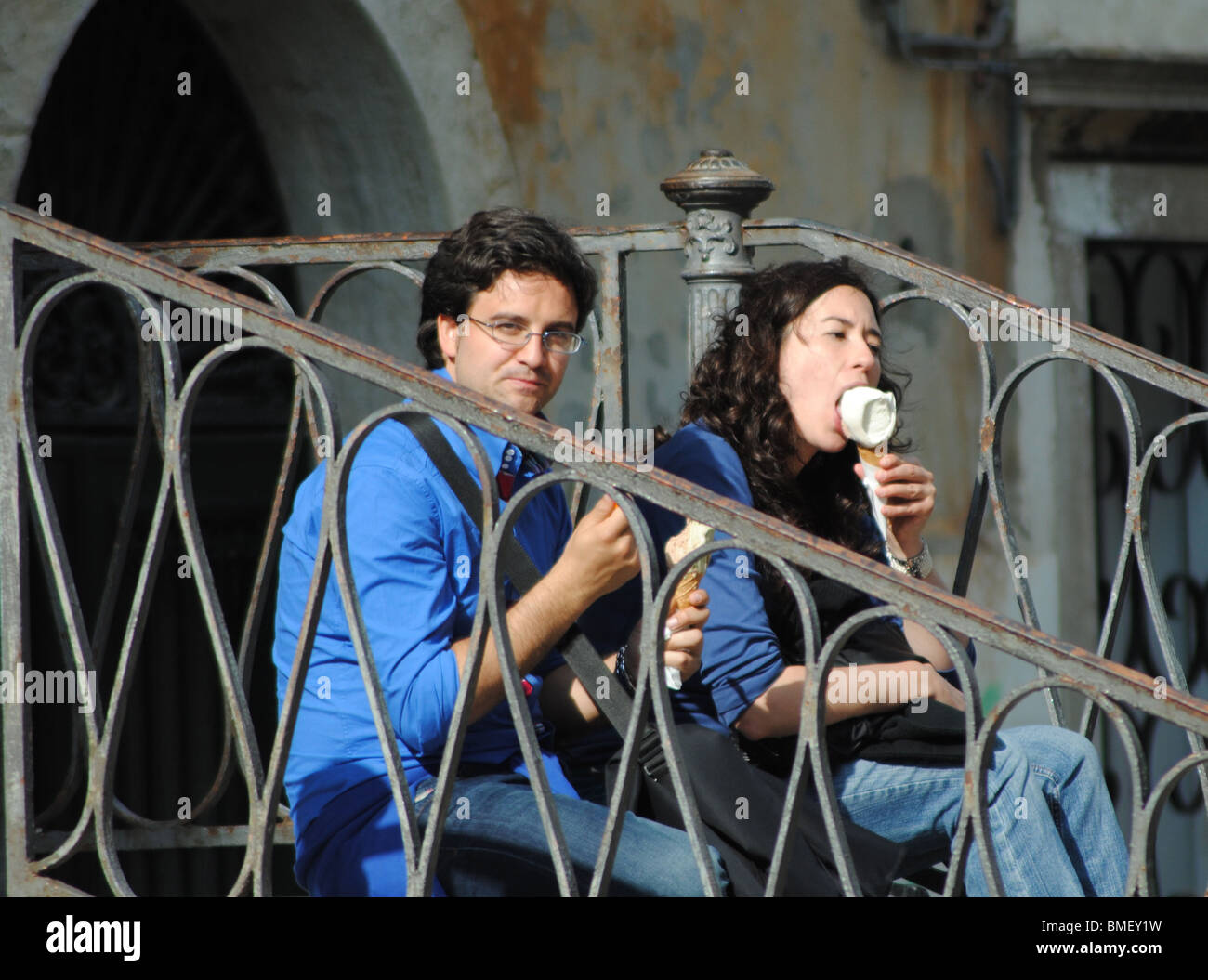 Tourists eat ice creams, sitting on a bridge in Venice, italy Stock Photo