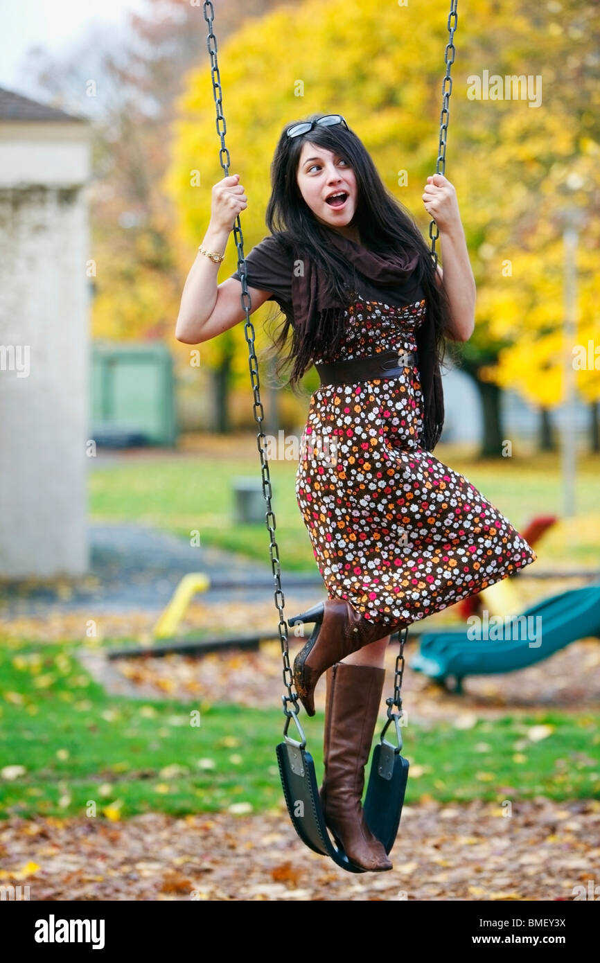 A Young Woman Standing On A Swing At A Playground In Autumn Stock Photo