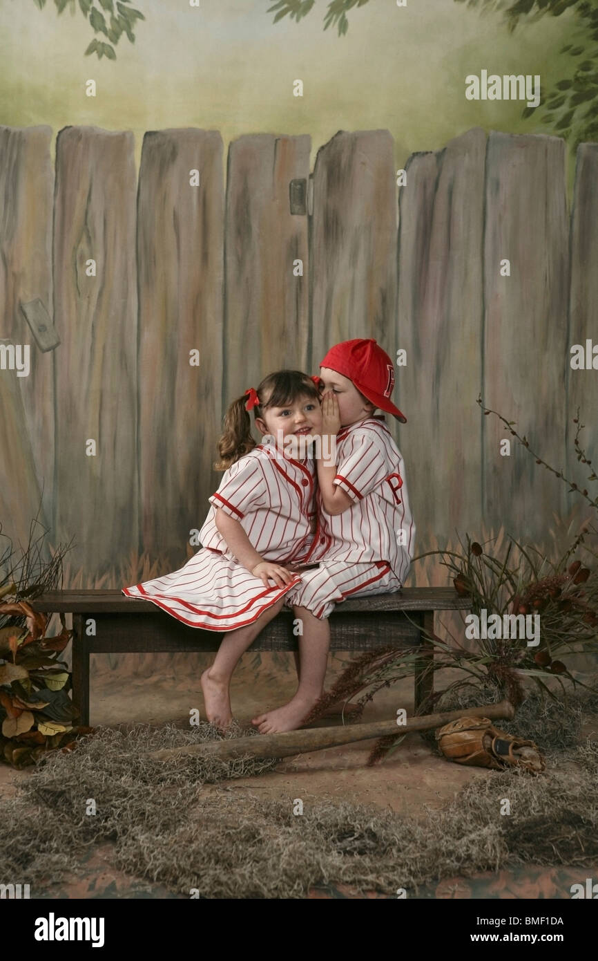 A Boy Whispering To A Girl Wearing Matching Baseball Uniforms Stock Photo