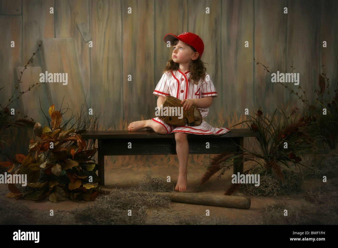 A Girl Sitting On A Bench Wearing A Vintage Girl's Baseball Uniform Stock Photo
