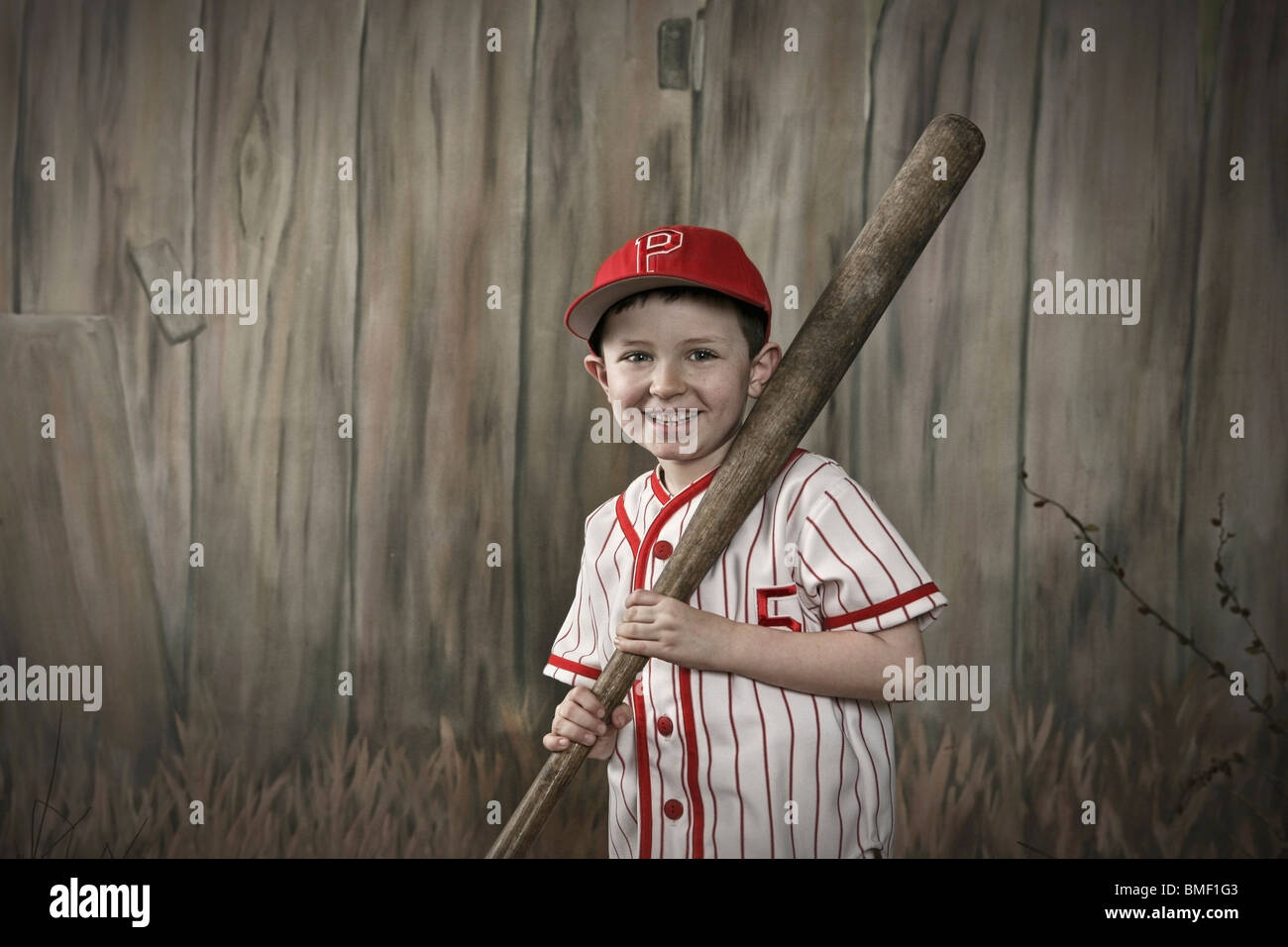 A Boy Wearing A Baseball Uniform And Holding A Bat Stock Photo